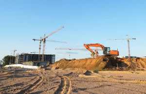 A wide view of a commercial construction project with equipment including cranes and earthmoving machines