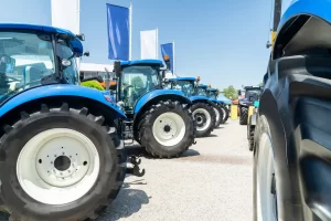 A line up of blue tractors with white wheels at a farming show on a sunny day