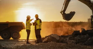 Construction workers on site with large equipment at sunrise